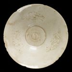 Bowl of porcelain with decoration incised under a qingbai glaze. Conical with six notches in the rim. The inside is engraved with three butterflies, surrounding a central medallion containing a yin-yang symbol