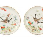 A pair of famille rose porcelain dishes with gilt foliate edges - faces decorated with black swallowtail butterflies and florals