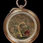 Gold locket, the frame edged with a serpent enclosing a drooping rose bush and a butterfly in enamelled gold